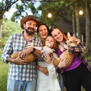OBBBA - Dependent Care FSA Limit and Employee Benefits Strategy; happy family outside - husband, wife, two daughters - holding small dogs